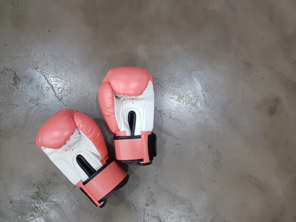 Picture of pink and white boxing gloves on a cement floor.