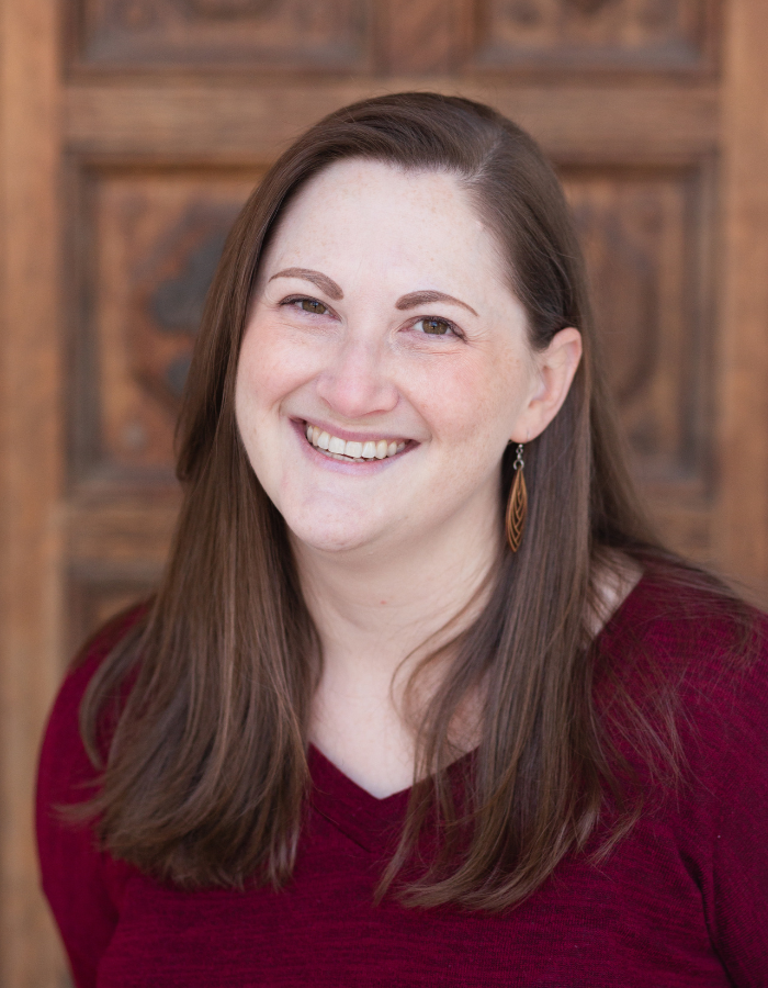 Image of Rachel smiling in front of a brown door.